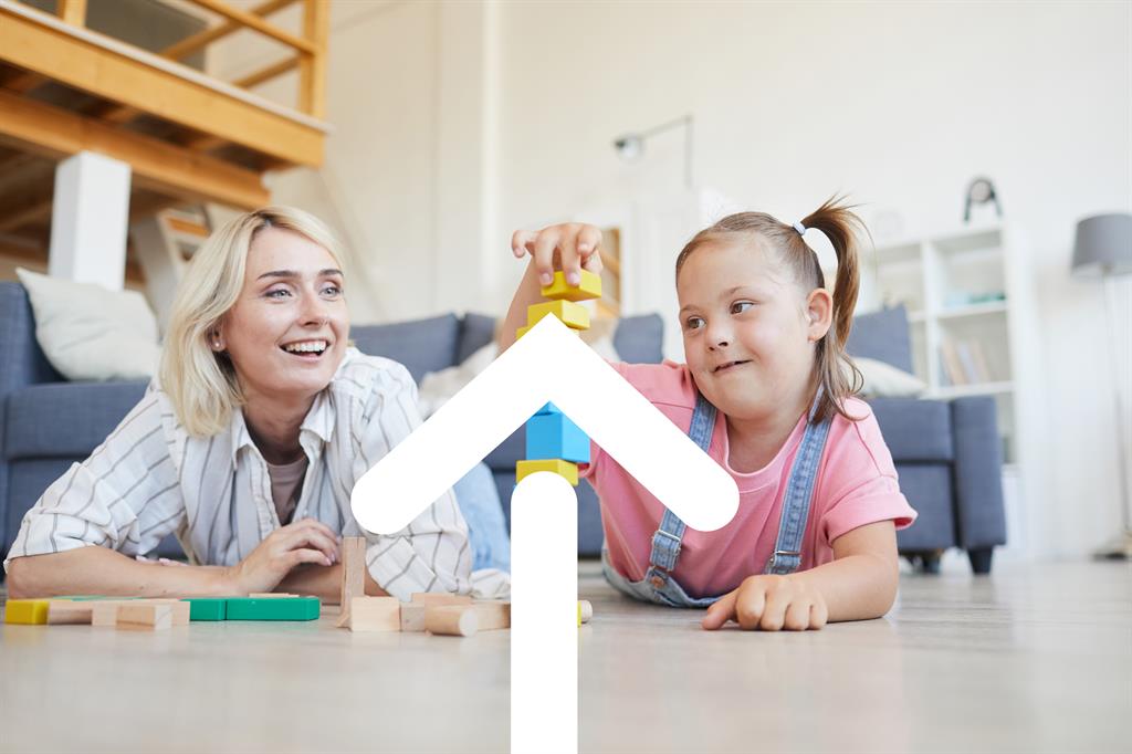 A mother smiles as she helps her daughter stack blocks